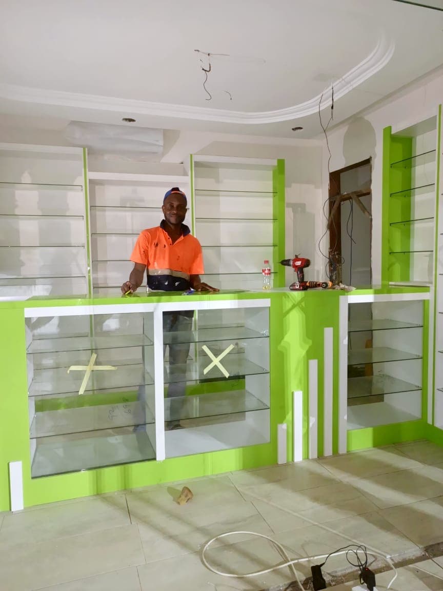 Tech1 Wood Works craftsman with completed retail shelving fit-out in Ghana